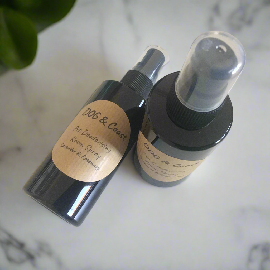 Two bottles of deodorising room spray with labels, one spray nozzle is black and the other is clear, placed on a marble surface.